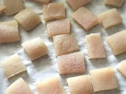 Sau khi đã nguội hẳn lọc lại những phần mỡ còn sót lại rồi thái bì thành miếng 2x2,5cm. Xếp bì lợn đều ra mặt mâm inox, trùm vải voan cho đỡ bụi rồi đem phơi nắng, nắng to tầm 2 ngày là da khô rồi. Ảnh: aMeovat.com.