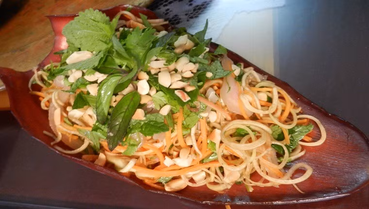 Cóc thái mỏng vừa ăn. Làm nước trộn: Tỏi ớt băm nhuyễn. Lấy đường, nước mắm, chanh hòa tan. Sau cùng cho tỏi ớt vào. Trộn đều tất cả lại với nhau. Chú ý sau khi trộn ăn liền để bì heo không bị ỉu nhé. Ảnh: huongsen.vn.