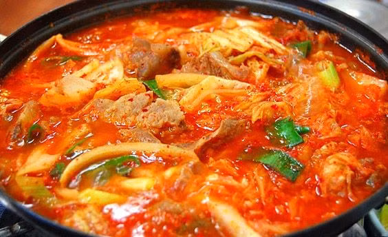 Cho kim chi vào đảo trong 1 phút sau đó thêm khoảng 120ml nước dùng vào. Đậy vung, đun trong 7 phút ở lửa vừa. thêm muối, đường vào, khuấy đều. Tiếp theo, cắt đậu hũ rồi dùng thìa dầm nhỏ đậu hũ ra. Ảnh: Thucthan.com.