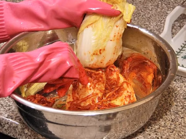 Cho hành tây, tỏi, táo, gừng vào máy xay sinh tố, đậy nắp xay nhuyễn hỗn hợp. Cho hỗn hợp vừa xay ra âu to, thêm nước sốt đã nguội cùng với hành lá, hẹ, củ cải, cà rốt, bột ớt, muối tôm trộn đều nguyên liệu. Ảnh: Comvo.vn.