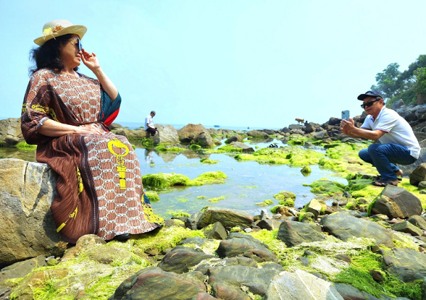 Hai vợ chồng người Hà Nội đang du lịch tại Đà Nẵng cũng tranh thủ ngày nắng đẹp đến lưu giữ khoảnh khắc đẹp tại rạn Nam Ô vào mùa rêu xanh. Ảnh: MINH TRƯỜNG. 