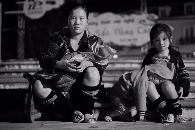Phó nháy Phạm Nhất Việt, sinh năm 1987 - chủ nhân của những bức ảnh này cho biết, anh chụp ảnh vào thời điểm khoảng 22h giờ đêm, trong một phiên chợ tình ở Sa Pa. Nơi anh Việt chụp ảnh có khá nhiều bà mẹ người dân tộc H'mông mang các con của mình đến phiên chợ bán hàng. Trời khi đó khá lạnh và bé gái xinh xắn, mặc trang phục truyền thống của người H'mông đã dùng chân để làm gối cho em trai còn rất nhỏ của mình nằm ngủ gục lên trên. Bị cuốn hút hoàn toàn vào đôi mắt và vẻ xinh xắn của bé gái, anh Việt mua hàng cho mẹ con bé, bắt chuyện và lén ghi lại một số khoảnh khắc rất đẹp. Ảnh:Phạm Nhất Việt.