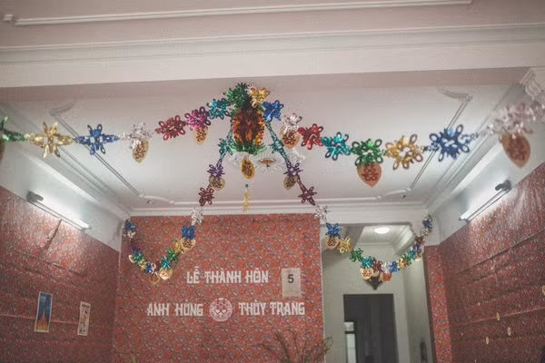 Tường căn phòng nơi diễn ra lễ thành hôn của cặp đôi 8X được dán giấy in hình hoa hồng, hoa mai - họa tiết đặc trưng của những năm 70-80 khiến các vị khách trung niên liên tưởng ngay đến những gì mình đã trải qua trong quá khứ. Do khoảng cách về thời gian nên để tìm được những món đồ trang trí này, cả nhà chú rể đã tốn rất nhiều công sức.