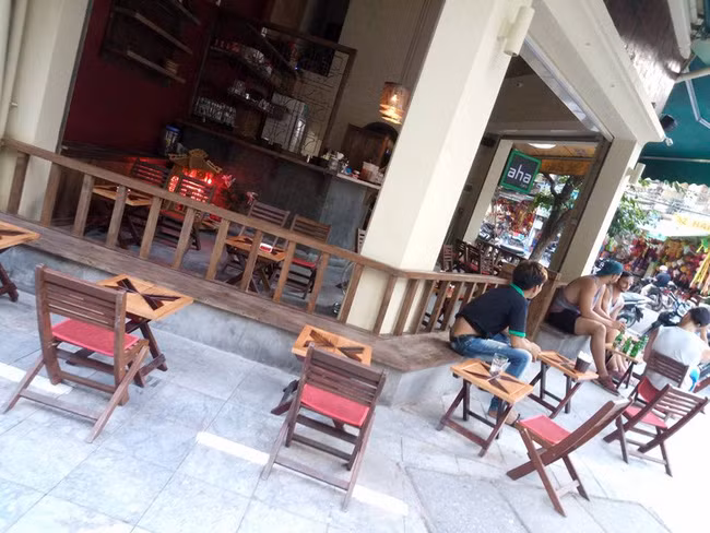 Dù không có thiết kế mang phong cách đặc biệt nào nhưng Aha Cafe phố Thuốc Bắc lại hấp dẫn được nhiều vị khách yêu thích sự mộc mạc, giản dị, không chú trọng hình thức. Những vị khách đến đây có thể vừa nhâm nhi đồ uống, vừa ngắm phố xá tấp nập và trò chuyện với bạn bè một cách thoải mái. Do được thiết kế nhỏ gọn, khá nổi bật vì nằm ở đầu ngã 3, lại đặt tại khu trung tâm nên hàng ngày quán cũng đón rất nhiều lượt khách nước ngoài tiện chân ngồi giải khát. Ảnh: FB Mắt Híp.