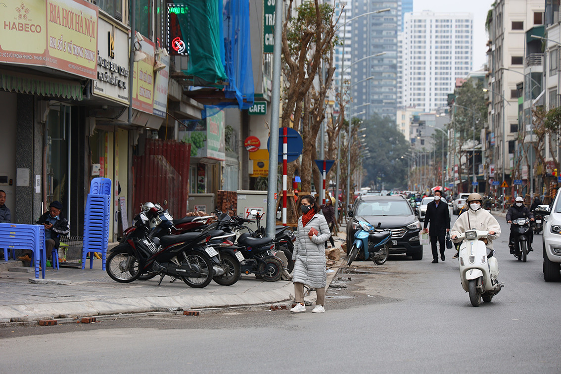 Việc vỉa hè bị lấn chiếm khiến người đi bộ buộc phải xuống lòng đường để di chuyển.