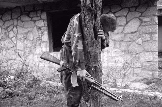 Một người lính Bosnia ôm gốc cây ở phía sau vườn nhà anh ta. Tại nơi này, cả gia đình anh cùng toàn bộ hàng xóm đã bị hành quyết bởi lực lượng Serbia. Nguồn ảnh: Proboard.