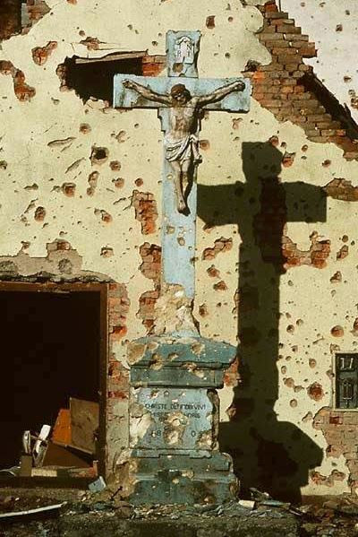 Cây thánh giá bên trong một nhà thờ thuộc vùng kiểm soát của Croatia vẫn còn gần như nguyên vẹn dù toàn bộ nhà thờ đã bị đổ sập do hoả lực của các bên. Nguồn ảnh: Proboard.