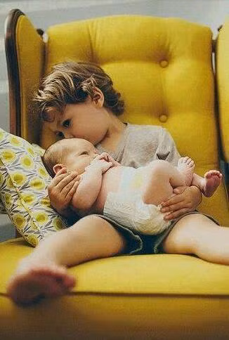 Anh bế em khi mẹ bận việc.