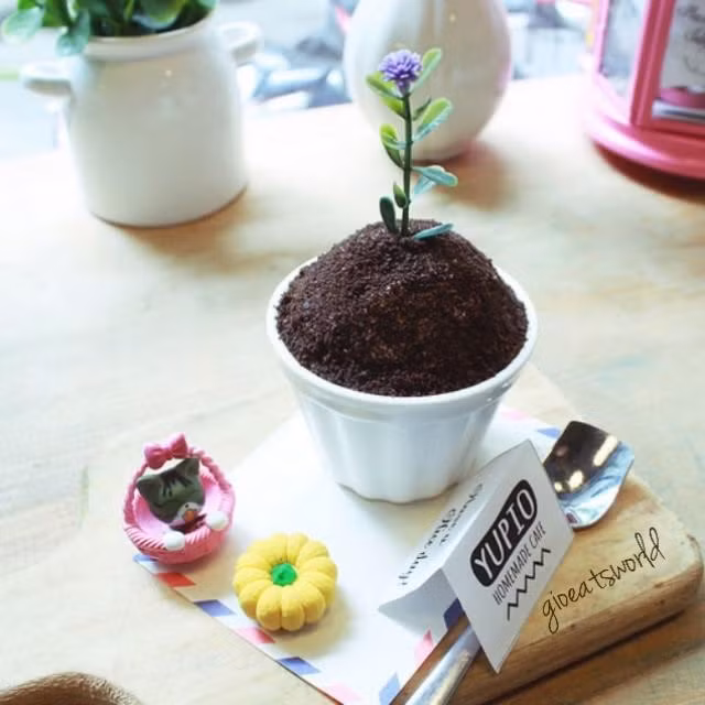 Một phần bánh chậu cây với cốc có hình chậu cây và thìa tạo hình xẻng xới đất dễ thương. Nếu không được chủ quán giới thiệu, nhiều người sẽ lầm tưởng đây là một chậu cây thực sự.