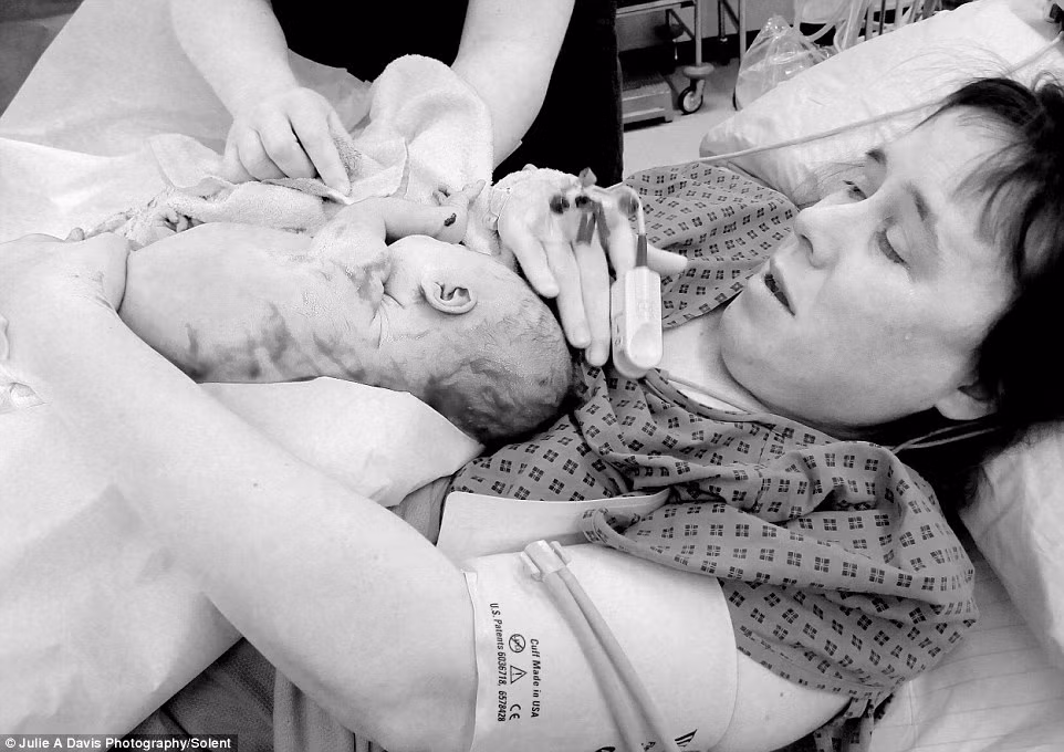 Cô Julie Davis, 45 tuổi đến từ Ashurst, Hampshire sẵn sàng đến bất cứ nơi nào để cho ra đời những bức ảnh sinh nở chân thực nhất. Trong hình là giọt nước mắt hạnh phúc của người mẹ khi lần đầu được ôm con gái bé bỏng vào lòng.