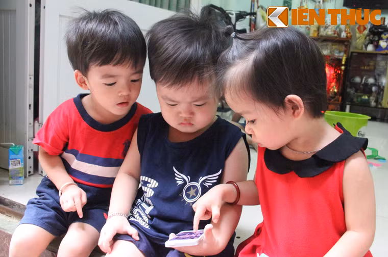 Lần lượt những cái tên ở nhà của các con được vợ chồng chị Thư đặt theo thời điểm mỗi đứa được bác sĩ đưa ra từ bụng mẹ: Cả; Hai; Ba; Tư; Út. Trong ảnh là anh Ba (ngồi giữa) đang được đứa em gái út "hướng dẫn" sử dụng ĐTDĐ trong khi anh hai (bìa trái) cũng chăm chú nhìn 2 em của mình.