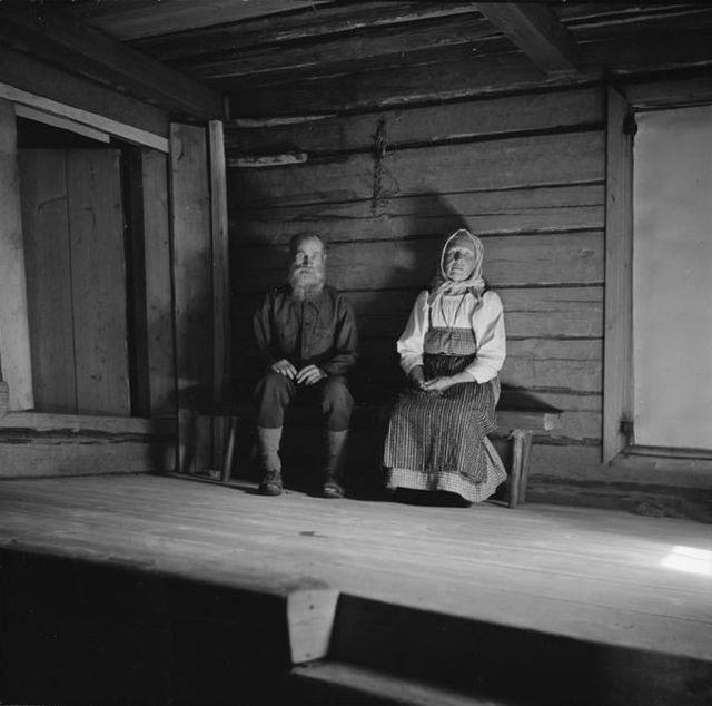 Cặp vợ chồng lớn tuổi người Liên Xô ngồi trong căn nhà gỗ.