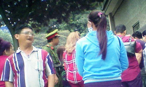 Sáng 23-5, trước Tổng lãnh sự quán Trung Quốc tại TP.HCM, cò” C. (áo sọc) rao “bán chỗ” xếp hàng vào làm visa trước với giá 400.000 đồng - Ảnh: S.BÌNH