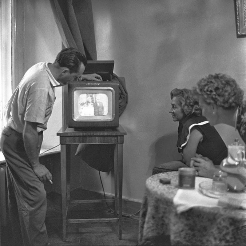 Một gia đình quây quần tại phòng khách cùng xem chương trình tivi.