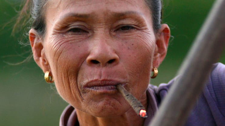 Gương mặt một phụ nữ địa phương đang chèo thuyền dọc theo con sông hướng về chợ Hội An trong buổi hoàng hôn.