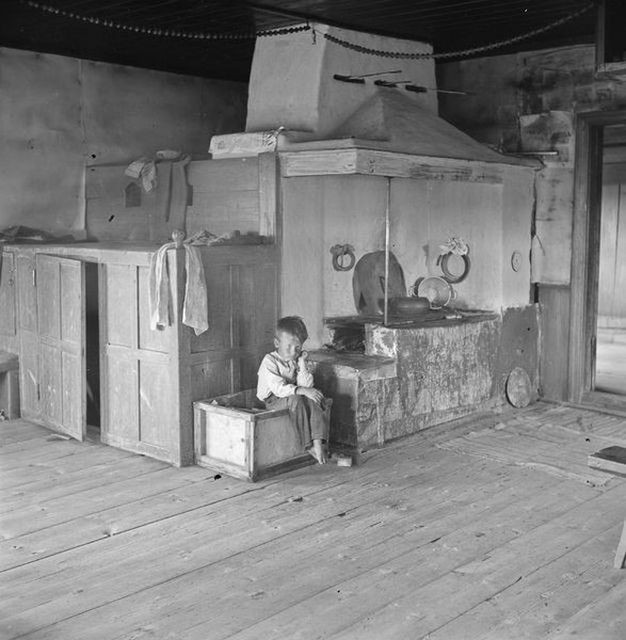 Bé trai ngồi chơi một mình trong căn nhà rộng.