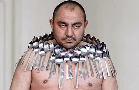 Người đàn ông có tên Etibar Elchiyev xác lập kỷ lục với việc giữ 53 chiếc thìa kim loại trên ngực mình. Ảnh Oddee.