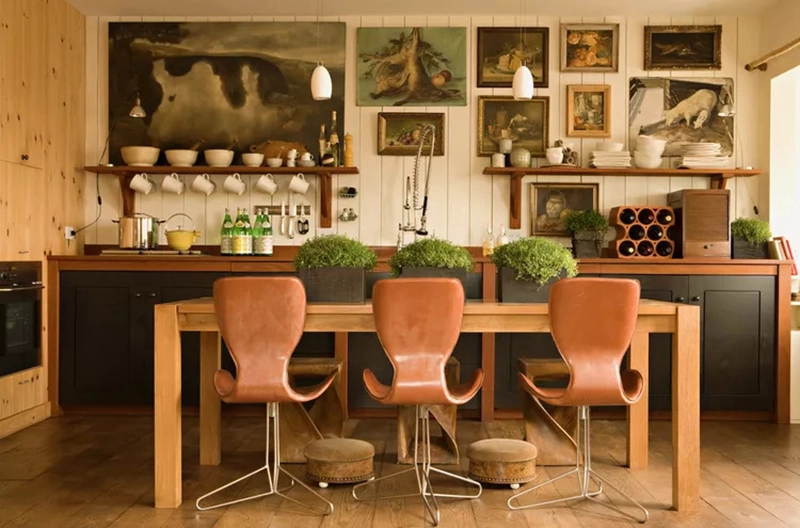 2. Nhà bếp mang phong cách boho ấm cúng làm chúng ta choáng ngợp ngay khi vừa đặt chân tới. Bức tường trong phòng được tạo ra bằng cách ghép nhiều tấm ván lại với nhau. Tại đây, chủ nhân căn phòng đã biến bức tường thành một không gian trưng bày ấn tượng với những bức tranh cổ điển. Trên bàn ăn, 3 chậu cây có vai trò tăng thêm chút tươi mát, trong lành cho bầu không khí bên trong căn bếp nhỏ.