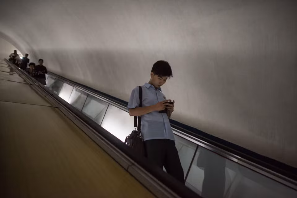 Một thanh niên dùng điện thoại di động trong ga tàu điện ngầm ở Bình Nhưỡng. Theo songbun, cư dân được phép sinh sống ở Bình Nhưỡng là hậu duệ và họ hàng của những người đã sát cánh cùng lãnh tụ trong các cuộc chiến những thập niên trước, hoặc có mối quan hệ thân tình, gần gũi với lãnh tụ. Ảnh: Getty.