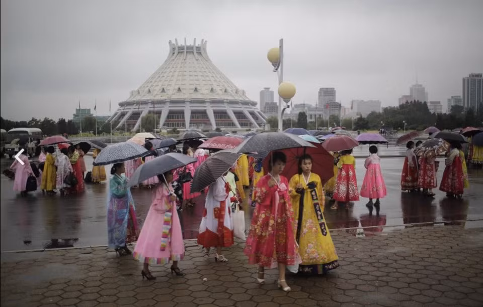 Các cô gái đội mưa chờ giờ cử hành vũ hội. Đời sống tinh thần của giới trẻ Bình Nhưỡng rất phong phú với những sự kiện giải trí lớn gắn liền với các sự kiện chính trị của dân tộc. Ảnh: AP.