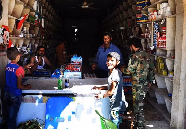 Bé trai cười tươi khi mua đồ trong một cửa hàng ở Đông Aleppo. Ảnh: FNA.