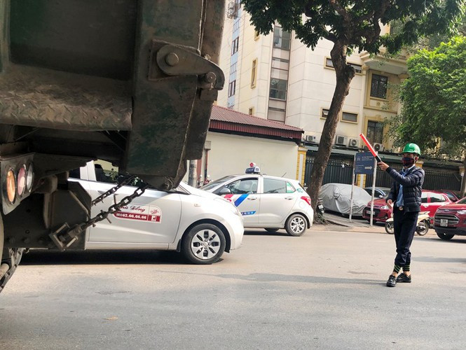 Ngoài xe đừng trên đường chờ được vào công trường, mỗi khi có xe ra vào công trường nhân viên thi công tại đây còn cầm dùi cui nhựa ra giữa đường cản phương tiện trên đường để xe tải di chuyển..