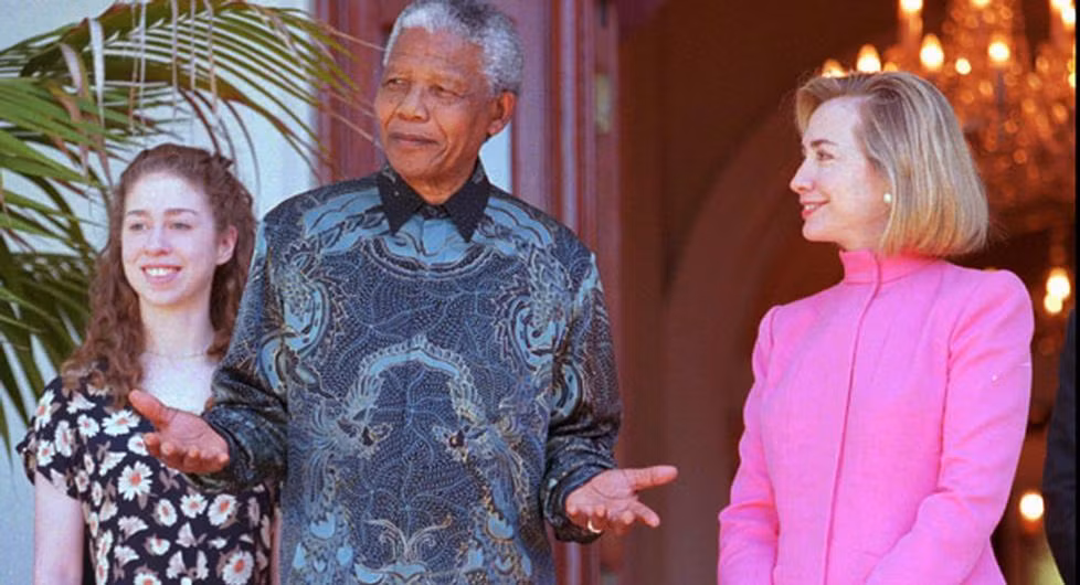 Khi còn là "đứa trẻ đệ nhất", Chelsea cũng đã được đi cùng cha mẹ tới nhiều nơi trên thế giới. Ảnh: Chelsea (trái) đứng cạnh Tổng thống Nam Phi Nelson Mandela trong chuyến thăm quốc gia Châu Phi này cùng cha mẹ cô ngày 20/3/1997. Ảnh: AP.