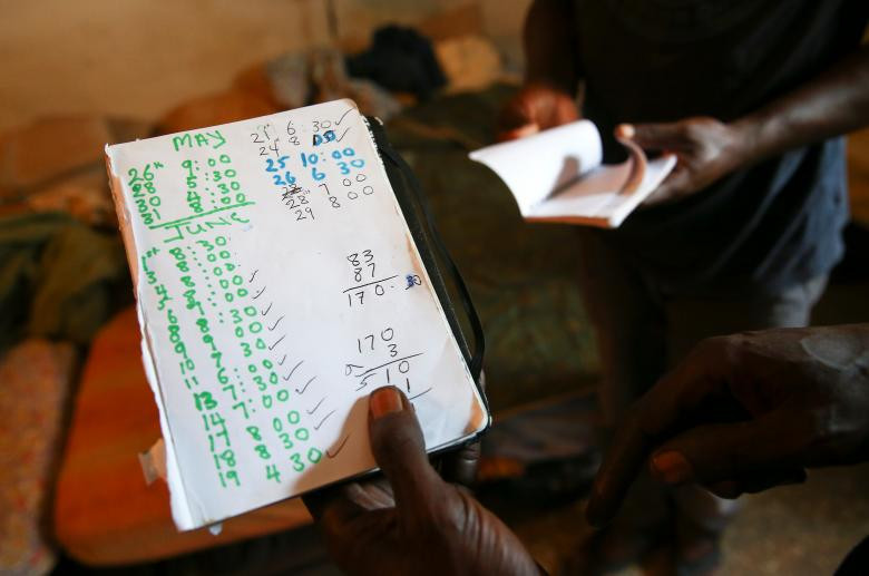 Sutay Darboe, 42 tuổi đến từ Senegal, cầm tờ giấy ghi cụ thể số ngày và giờ anh làm việc mỗi ngày.