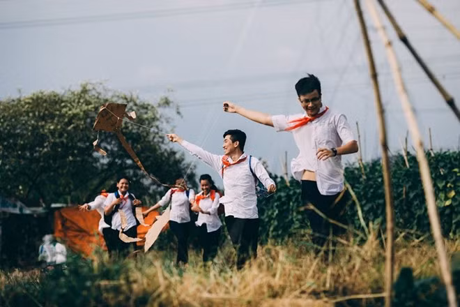 Sau giờ học mệt mỏi, các bạn rủ nhau chơi trò thả diều trên cánh đồng một cách vui vẻ, hồn nhiên.