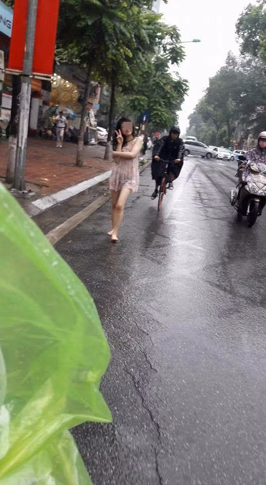 Cô gái trẻ khoảng 23-24 tuổi, mặc trang phục giống như đồ ngủ ở nhà, mỏng tang để lộ cả nội y. Dù vậy, cô nàng vẫn rất thoải mái đi lại và tắm mưa giữa phố bất chấp vô số ánh mắt của người đi đường đang hướng về mình.