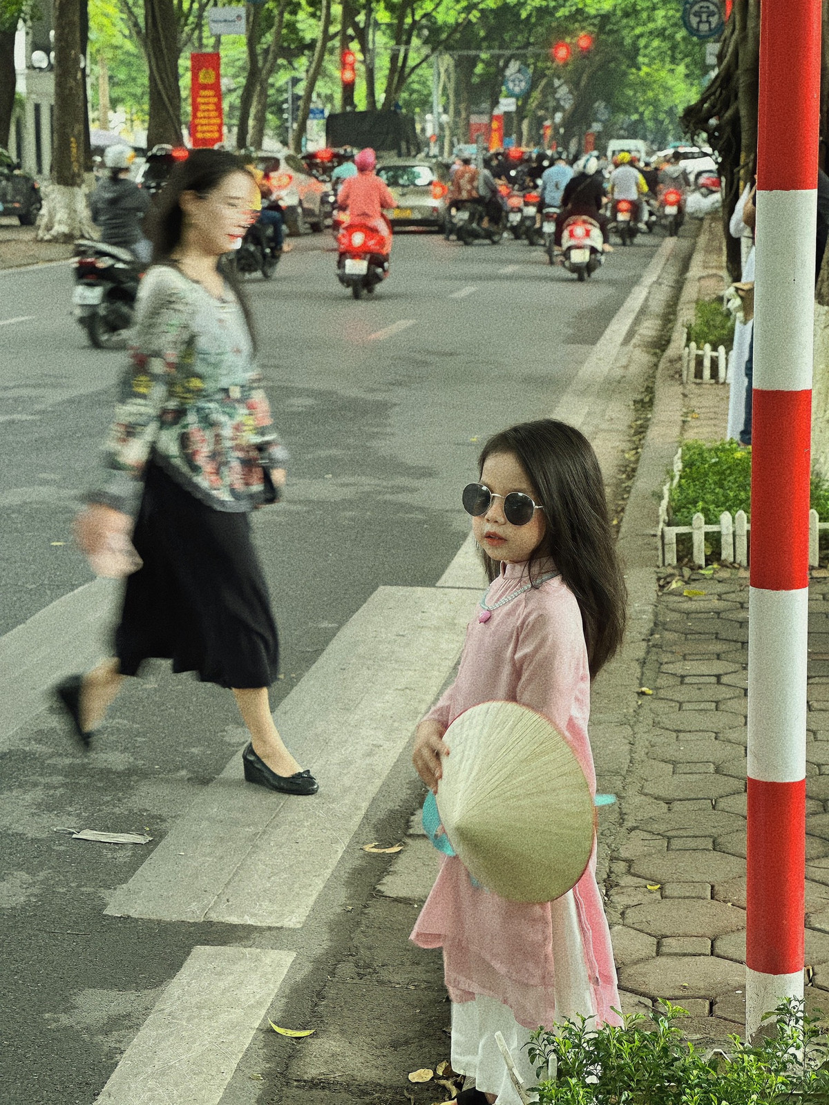 Diện trên mình bộ áo dài màu hồng phấn, cầm trên tay chiếc nón lá, đi đôi guốc mộc, điểm thêm đôi kính dễ thương, cô bé trở thành "nhân vật chính" ở bất cứ địa điểm nào đi qua. Ảnh: Hong Anh