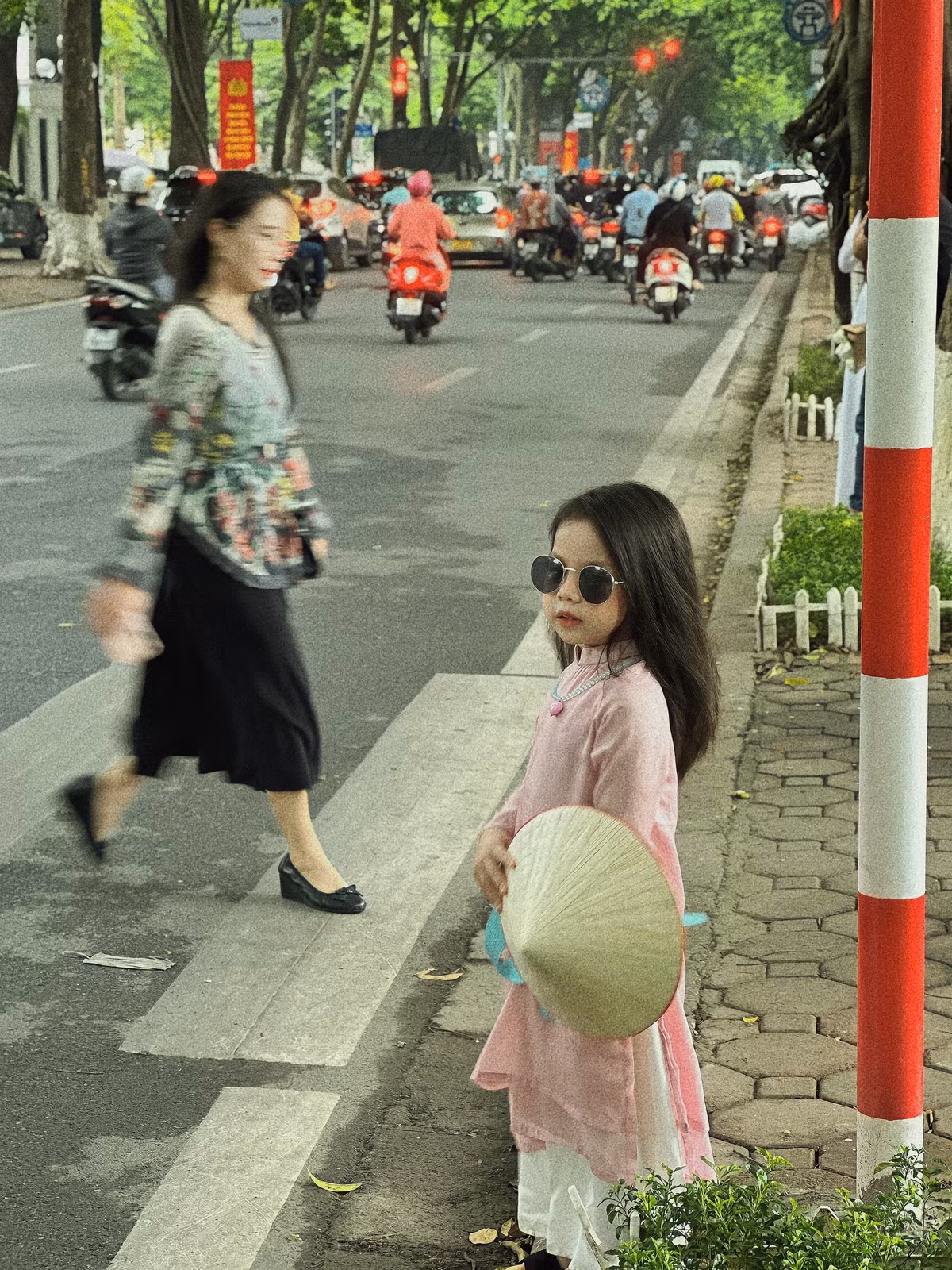 Diện trên mình bộ áo dài màu hồng phấn, cầm trên tay chiếc nón lá, đi đôi guốc mộc, điểm thêm đôi kính dễ thương, cô bé trở thành "nhân vật chính" ở bất cứ địa điểm nào đi qua. Ảnh: Hong Anh