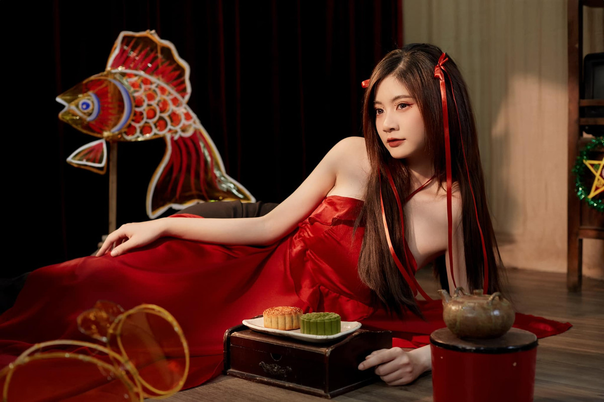 Trong bộ ảnh này, "hot girl má lúm" diện váy yếm màu đỏ, tạo dáng trong khung cảnh đậm chất truyền thống mùa Trung thu là những chiếc bánh, ấm trà và đèn lồng con cá chép,...