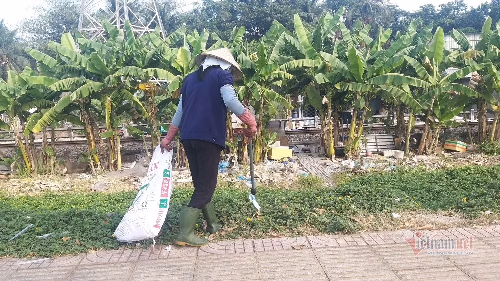 Trước cảnh khẩu trang vứt bỏ tràn lan trên đường Phạm Văn Đồng, nữ công nhân vệ sinh phải đi thu gom từng chiếc
