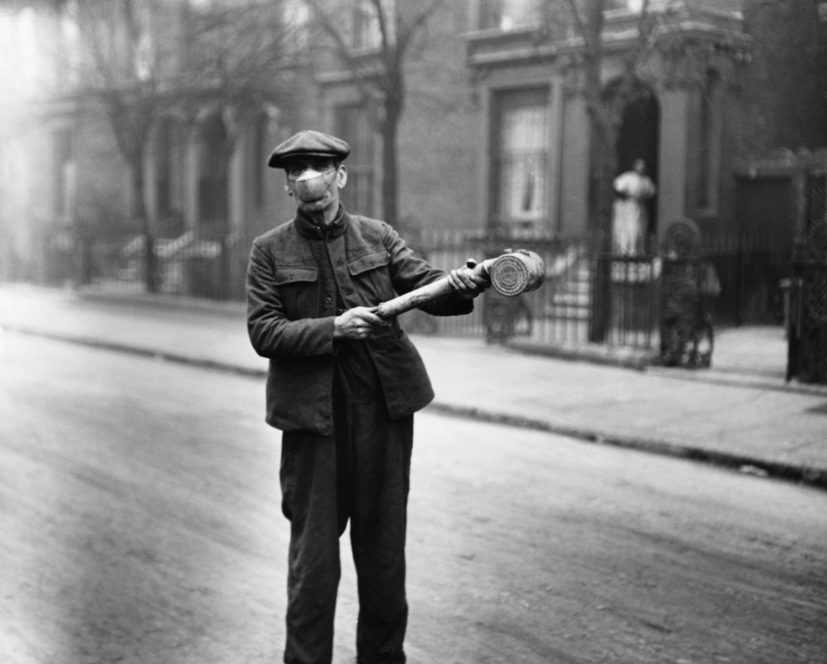 Người đàn ông ở Anh đeo mặt nạ và tay cầm một bình xịt để phun thuốc khử trùng trong bối cảnh đại dịch cúm diễn ra hết sức nguy hiểm.