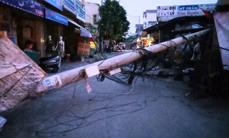 Tại hiện trường, cột điện nằm chắn ngang đường vào chợ, phần mái của tiệm sửa xe bị hư hỏng nặng, dây điện, dây cáp viễn thông bị kéo đứt nằm ngổn ngang dưới đường...