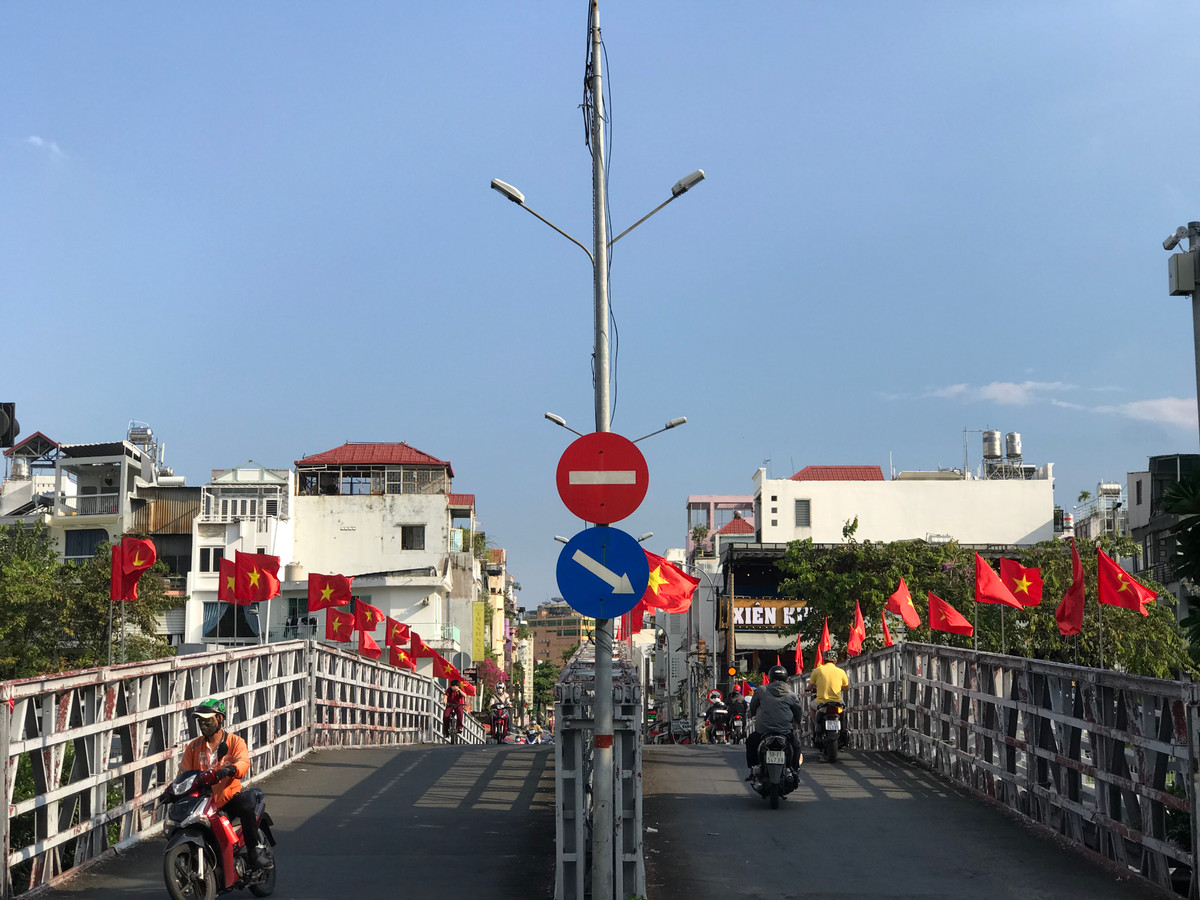 Hai bên đường, cờ đỏ sao vàng xen lẫn cờ búa liềm tung bay trong nắng tháng Tư, tạo nên khung cảnh trang nghiêm và rực rỡ.