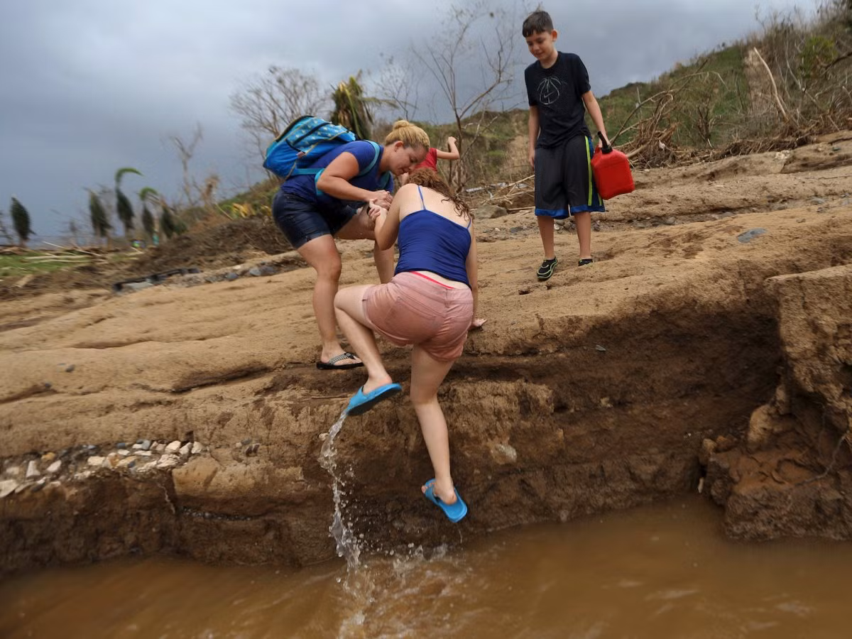 Một cô gái được đưa lên bờ sau khi lội qua sông ở Morovis. Ảnh: BI.
