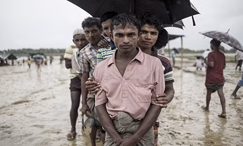 Người tị nạn Rohingya đứng xếp hàng chờ nhận thực phẩm được phân phát dưới trời mưa tại khu trại tị nạn Nayapara ở huyện Ukhia ngày 6/10. Ảnh: The Atlantic.