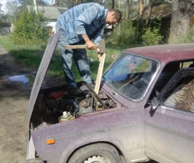 Người đàn ông dùng búa để sửa ô tô. Ảnh: ER.