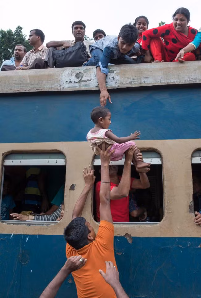 Mọi người đang cố gắng đưa một em bé lên nóc trước khi tàu chuyển bánh. Ảnh The Sun