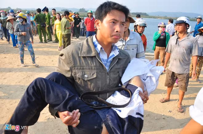 Một người đưa thi thể học sinh lên bờ.