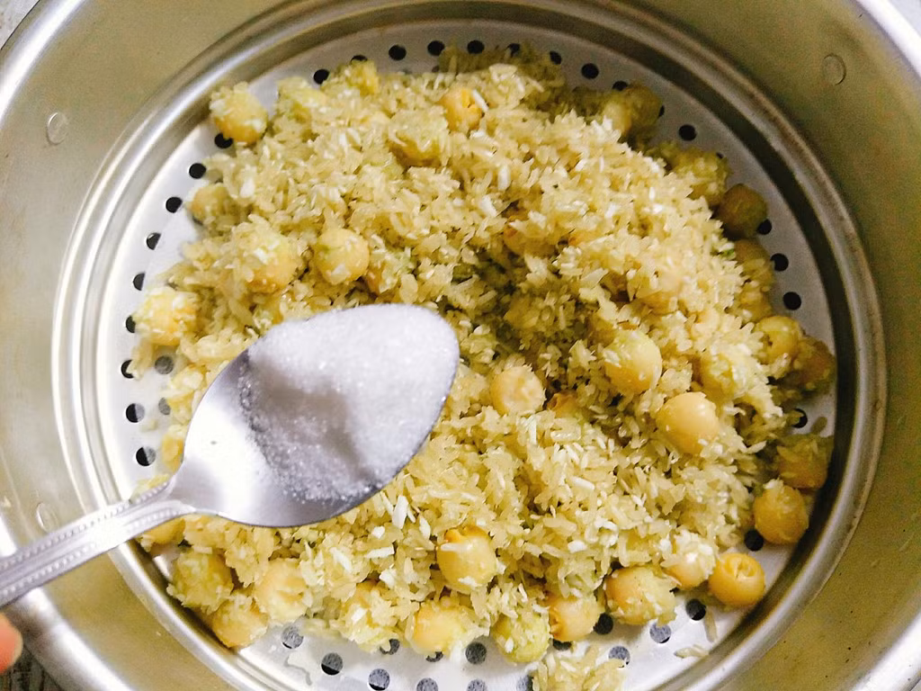 Nếu thích ăn ngọt, cho đường và dùng đũa xới đều xôi, đậy nắp vung hấp thêm 3 phút là tắt bếp, bỏ xôi hạt sen lá dứa thơm ngon ra đĩa rồi rắc thêm dừa bào sợi lên và thưởng thức.