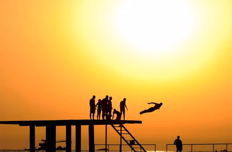 Mọi người thích thú trò nhảy cầu bên bờ biển khi hoàng hôn buông xuống.