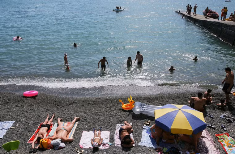 Mọi người thư thả tắm nắng trong khi một số khác đùa nghịch bên bờ biển. Ảnh chụp một bãi tắm ở Sochi những ngày mùa hè.