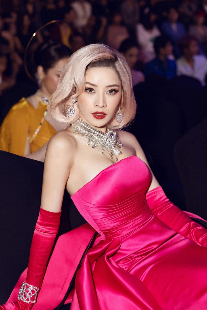 Chi Pu mặc nguyên bộ đầm lụa màu hồng. Đây được xem là gam màu kén chọn người mặc. Khá “cao tay”, dù chọn nhiều phụ kiện như vòng cổ, vòng tay, khuyên tai to bản đi kèm song người đẹp rất biết tiết chế khi chọn trang sức màu ánh kim. Thậm chí, cô cũng nhuộm tóc màu trung tính để tiết chế màu sắc.