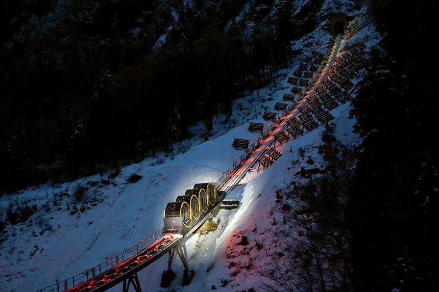 Trong ảnh, đoàn tàu toa thùng Stoosbahn chở khách đến khu trượt tuyết Stoos, Thụy Sĩ, vào ban đêm. Với độ nghiêng tối đa đến 110%, đây là đoàn tàu dốc nhất thế giới, theo sách Kỷ lục Guinness. Ảnh: Reuters.