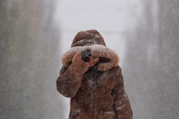 Người phụ nữ mặc áo khoác dày đi dưới mưa tuyết dọc theo một đại lộ ở trung tâm Kiev, Ukraine vào ngày 14/11.