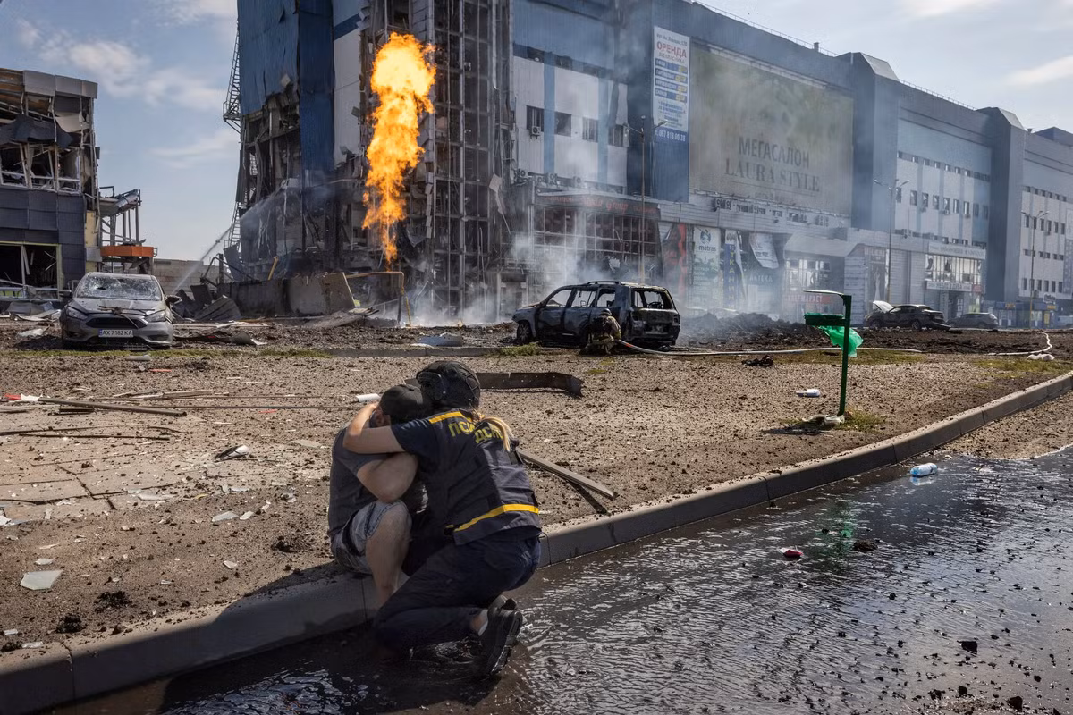 Trong bức ảnh, một nhân viên cứu hộ đang an ủi một người sống sót sau cuộc tấn công bằng tên lửa của Nga vào bãi đỗ xe của một cửa hàng ở Kharkiv.