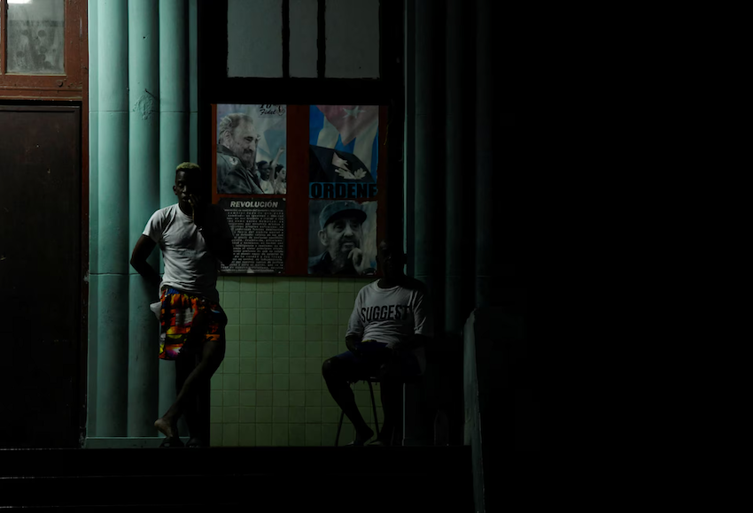 Sau khi chính phủ Cuba thông báo về những tiến bộ trong việc khôi phục điện, người dân đã tụ tập bên ngoài một tòa nhà, cạnh những bức ảnh của lãnh tụ Cuba Fidel Castro. Ảnh: Reuters.